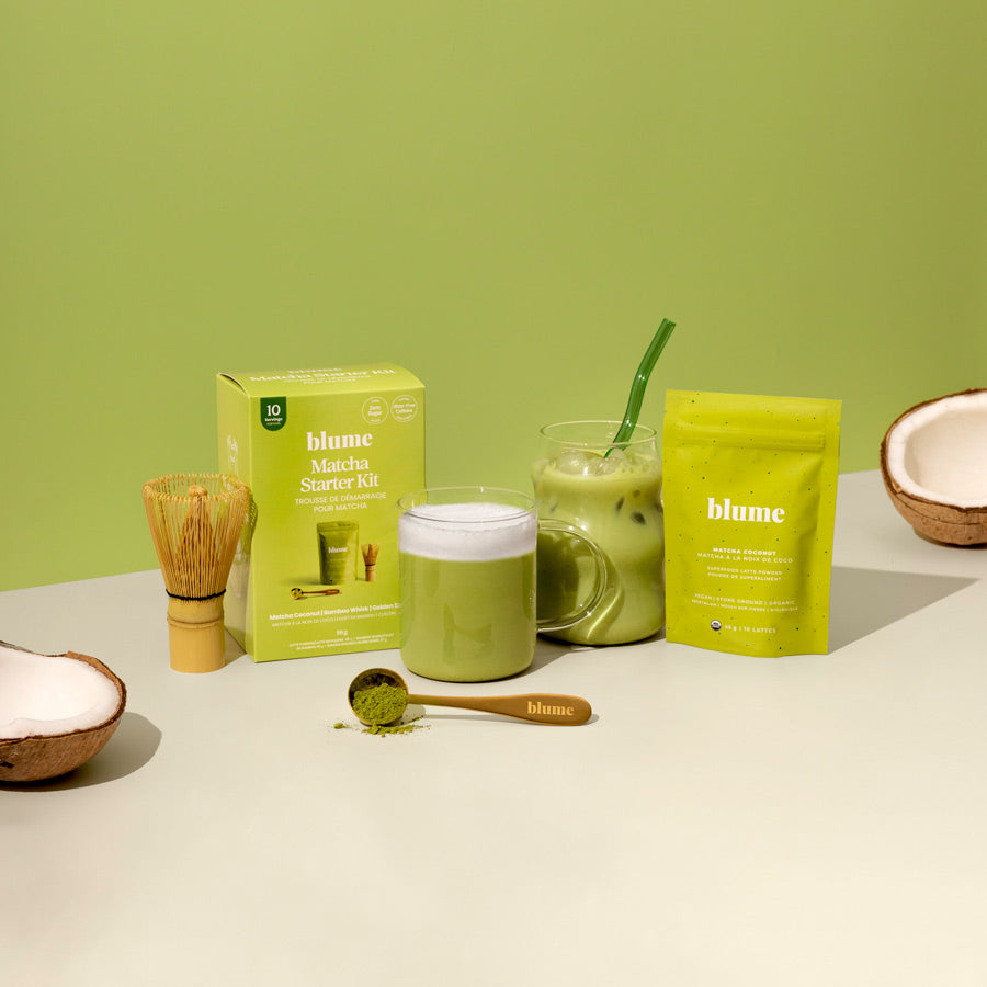 Our Matcha StarterKit comes in a box and contains a bamboo wooden whisk, a blume branded matcha measuring spoon and a packet of our matcha coconut. IN this picture we showcase the matcha latte as a hot drink in a glass mug and a iced in our bubble glass